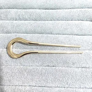 Close-up detail of a minimalist gold alloy U-shaped hair fork, elegant and sleek accessory.