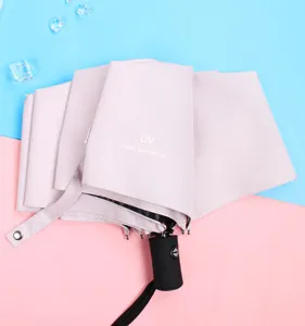 Primo piano dettagliato dell'ombrello UV rosa chiaro piegato con manico nero e stampa UV.