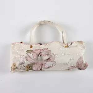 Three-fold sun rain umbrella with delicate floral lace embroidery and portable storage bag detail.