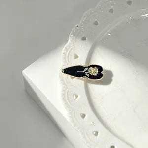 Close-up detail of a vintage French black and gold rose enamel side hair clip, elegant accessory.