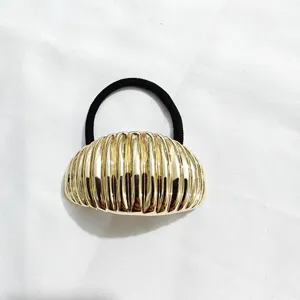 Primo piano dettagliato dell'elastico per capelli geometrico scanalato in metallo dorato.