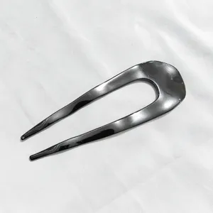 Dettaglio forcina per capelli a U nera, accessorio chignon minimalista, forcina superficie liscia.