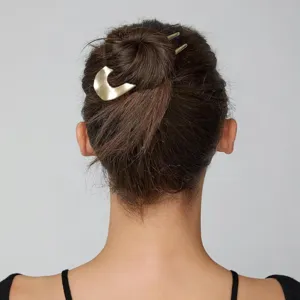 Dettaglio in primo piano dell'elegante forcina per capelli in metallo dorato a U.