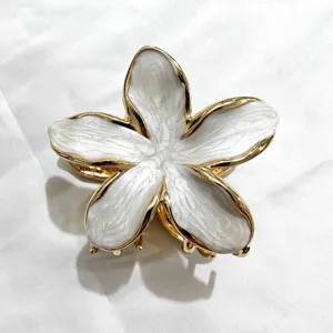 Primo piano dettagliato di una molletta per capelli a forma di fiore frangipani dorato.