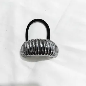 Primo piano di un semicerchio in metallo argentato scanalato con elastico per capelli.