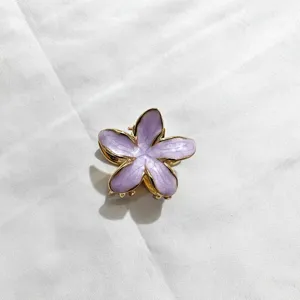 Elegante molletta per capelli con fiore di plumeria in smalto viola, finitura metallica.