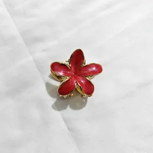 Vista dettagliata del fermaglio per capelli a fiore di frangipani rosso, elegante bordo dorato.
