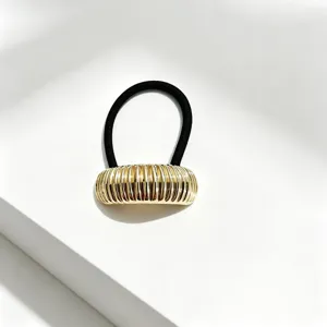 Dettaglio elastico per capelli in metallo dorato costato, accessorio geometrico minimalista.