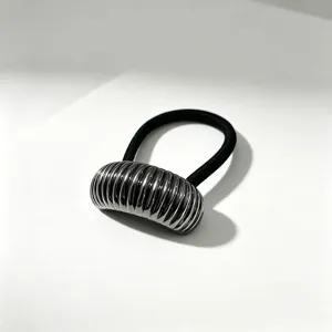 Primo piano del fermacapelli minimalista in metallo argentato costolato con elastico nero.