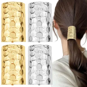 Dettaglio di polsini per coda di cavallo in metallo martellato oro e argento indossati da modella.
