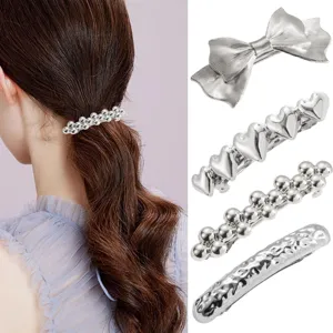 Close-up details of silver metal hair clips featuring bow, heart, and beaded styles.