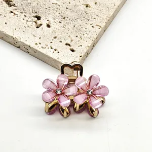 Detail shot of mini crystal flower hair claw clip in pink and gold, elegant side hair accessory