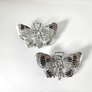 Gedetailleerde opname van zilveren vlinder haarclip met schedel ontwerp, uniek gothic accessoire.