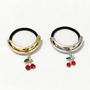 Close-up detail of glossy alloy hair tie featuring charming rhinestone cherry pendant and band.