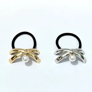 Close-up detail shot of minimalist metal bow hair ties featuring cute hanging pearl charms.