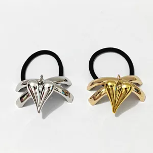 Detailed close-up of shiny alloy heart bow hair ties in silver and gold colors for women.