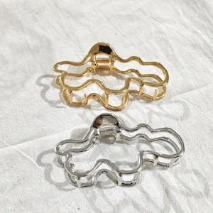 Nahaufnahme stilvoller Metall Haarklammern in Gold und Silber mit einzigartigem Wellendesign.