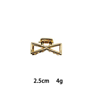 Detail view of the miniature gold alloy hair claw clip, featuring a geometric bow shape.