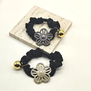 Elegantly designed black hair scrunchie with brilliant rhinestone flower and golden bell charm.