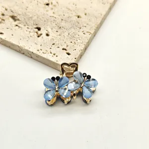 Mini blue crystal butterfly hair claw clip detail close-up, elegant metallic hair accessory.
