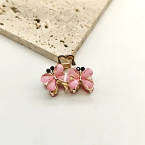 Detailed view of a mini crystal butterfly hair claw clip with pink rhinestones for elegant styling.