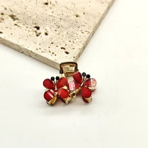 Detail view of a mini gold metal hair claw clip adorned with sparkling red crystal flower petals.