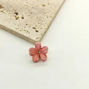 Detailed close-up of the mini crystal flower hair claw clip, showing sparkling pink floral petals.
