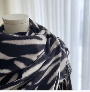 Close-up detail of women's black and white zebra striped scarf with soft tassel hem.