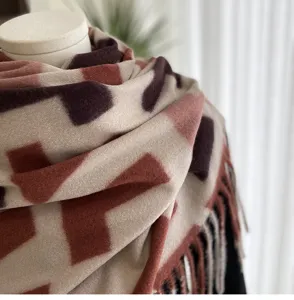 Close-up view of abstract geometric print cashmere-feel winter scarf with fringe detail.