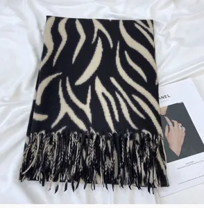 Detail view of black white zebra stripe fringe cashmere feel winter scarf fabric texture.