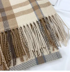 Close-up detail of winter cashmere-feel plaid scarf with fringe texture, warm cozy fabric.