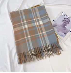 Detailed view of winter plaid tassel scarf in blue and brown colorway, soft texture.