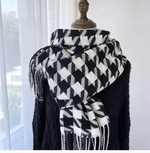 Detailed view of black and white houndstooth scarf with soft fringe, stylish winter neck wear.