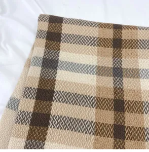 Close-up view of soft imitation cashmere scarf with classic beige and brown plaid pattern.