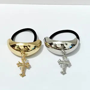Close-up detail of the metal arch hair tie with rhinestone cross pendant and elastic band.