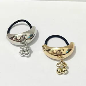 Detailed view of the metallic cherry hair tie featuring a glossy crescent alloy charm and elastic band.