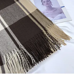 Close-up detail of soft plaid winter scarf with elegant fringe and warm brown beige tones.