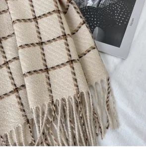 Close-up detail of cozy cashmere-feel grid scarf with stylish fringe and soft woven texture.
