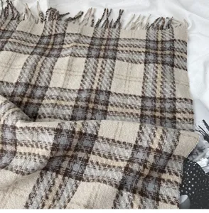 Classic plaid imitation cashmere scarf detail showing brown and blue pattern and soft fringe.