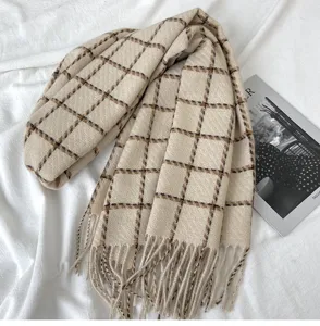 Close-up detail of the cozy beige and brown plaid scarf featuring soft fringe trim.