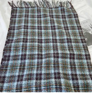 Detailed view of a cozy blue plaid winter scarf with fringe tassels, soft knit texture.