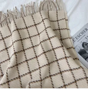 Detailed shot of cozy beige plaid scarf with fringe, soft cashmere-feel fabric for winter warmth.