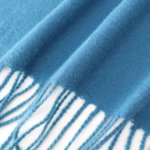 Close up view of soft blue winter cashmere feel scarf featuring delicate fringe details.