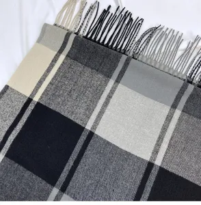 Close-up detail of classic black, grey, white and beige plaid scarf with soft fringe edges.
