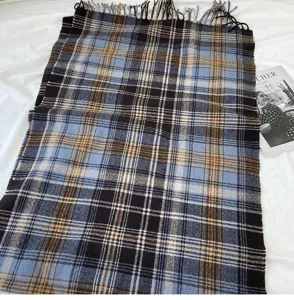 Classic blue and black plaid scarf detail showing soft fabric texture and fringe tassel trim.