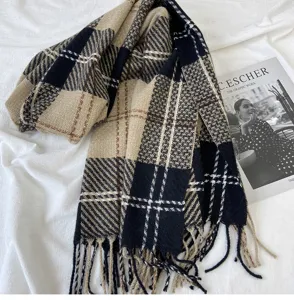Gros plan d'un écharpe à franges à carreaux d'hiver épaisse, motif classique noir et beige.