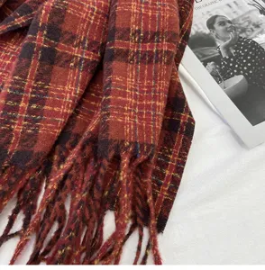 Detailed shot of a cozy red plaid winter scarf with classic tassels, soft textured warm fabric.