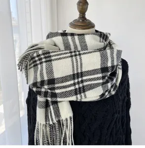 Gros plan d'écharpe à carreaux noirs et blancs, montrant le tissu doux et les franges.
