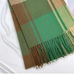Close-up detail of green and brown plaid winter scarf featuring elegant fringed edges.