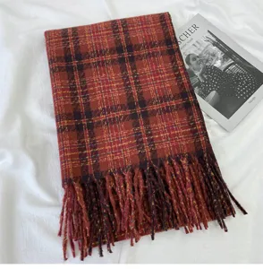 Detail shot of thick plaid scarf featuring warm Maillard tones and delicate fringe details.
